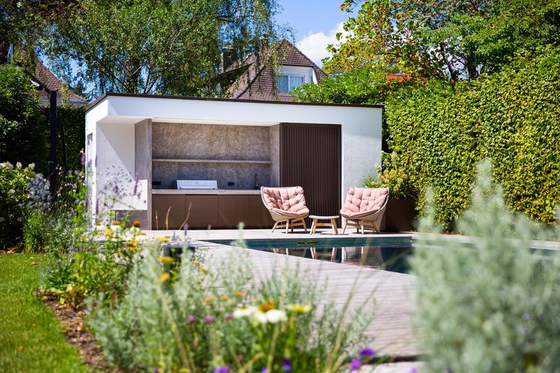 Edelstahl-Pool und Poolhaus hinter dem Staudenbeet